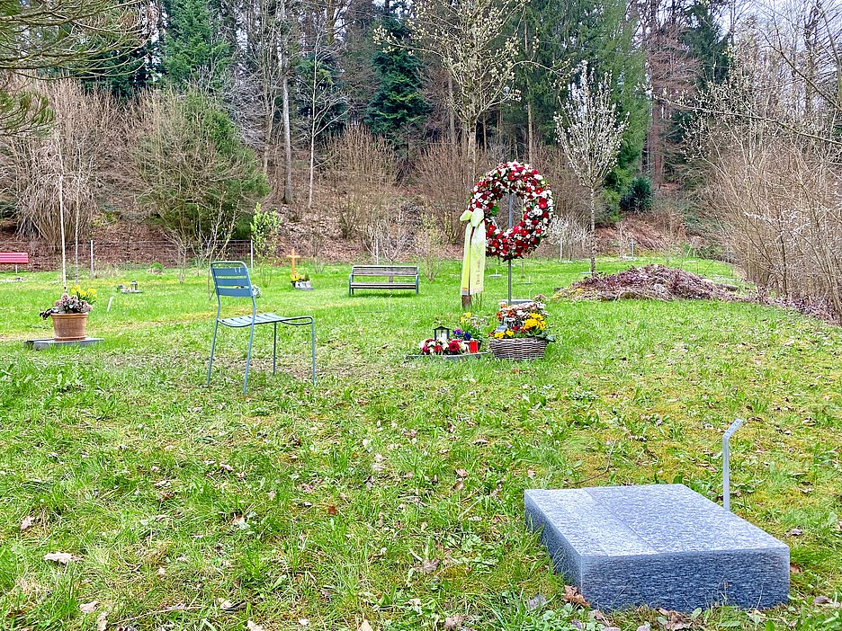 Der Bereich mit den Themengräbern «Wald» auf dem Friedhof Staffeln. Im Vordergrund eine noch unbenutzte Grabplatte, im Hintergrund ein Kranz bei einem neuen Grab.