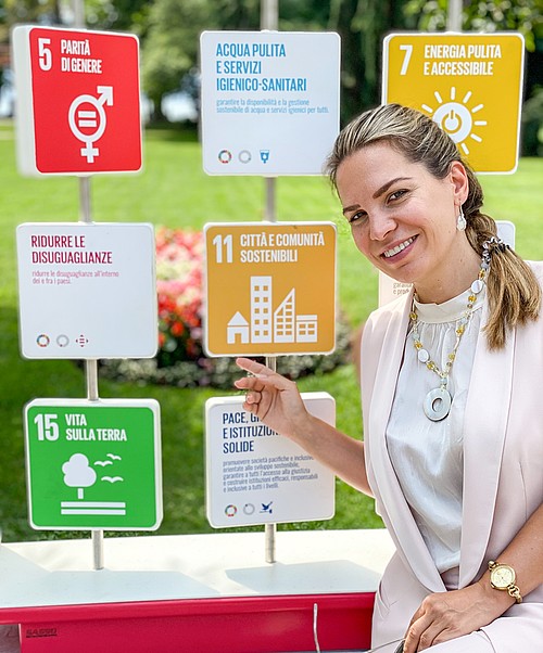 Ein bunter Abakus begrüsst die Passanten an einem der Eingänge des Parco Ciani, in der Nähe des Stadtzentrums: Er illustriert die 17 globalen Ziele für nachhaltige Entwicklung (Sustainable Development Goals, SDG) der UNO und das Projekt #LUGANOSOSTENIBILE. Auf dem Foto zeigt die Projektkoordinatorin Tatjana Ibraimovic das SDG 11 «Nachhaltige Städte und Gemeinden».