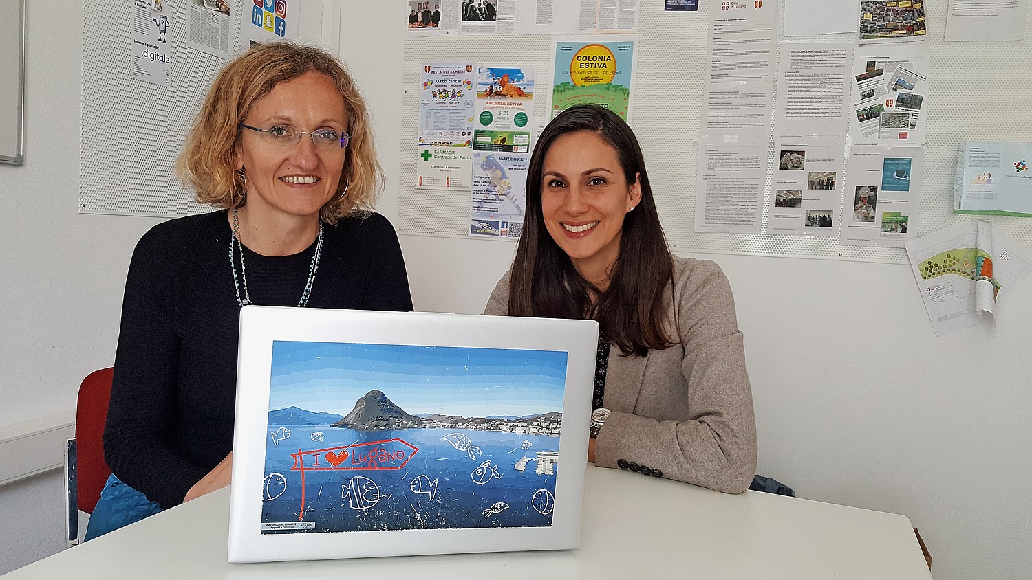 Monica Aliprandi, Leiterin des eQuiD-Projekts bei den Sozialen Diensten der Stadt Lugano (links) und Elena Marchiori, Projektverantwortliche vom Lugano Living Lab vor einem eQuiD-gestylten Laptop.